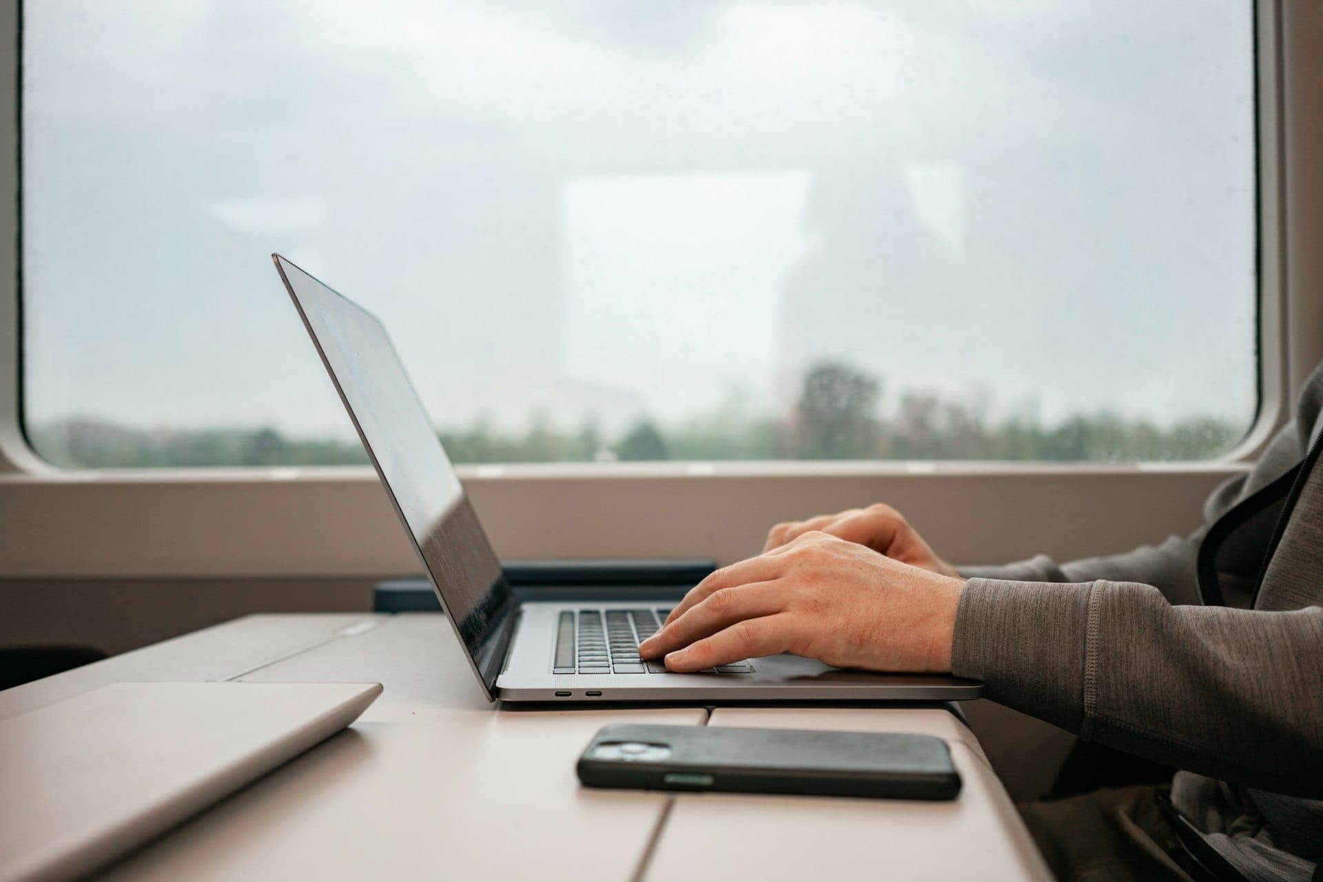 Person working on a laptop at a desk by a window