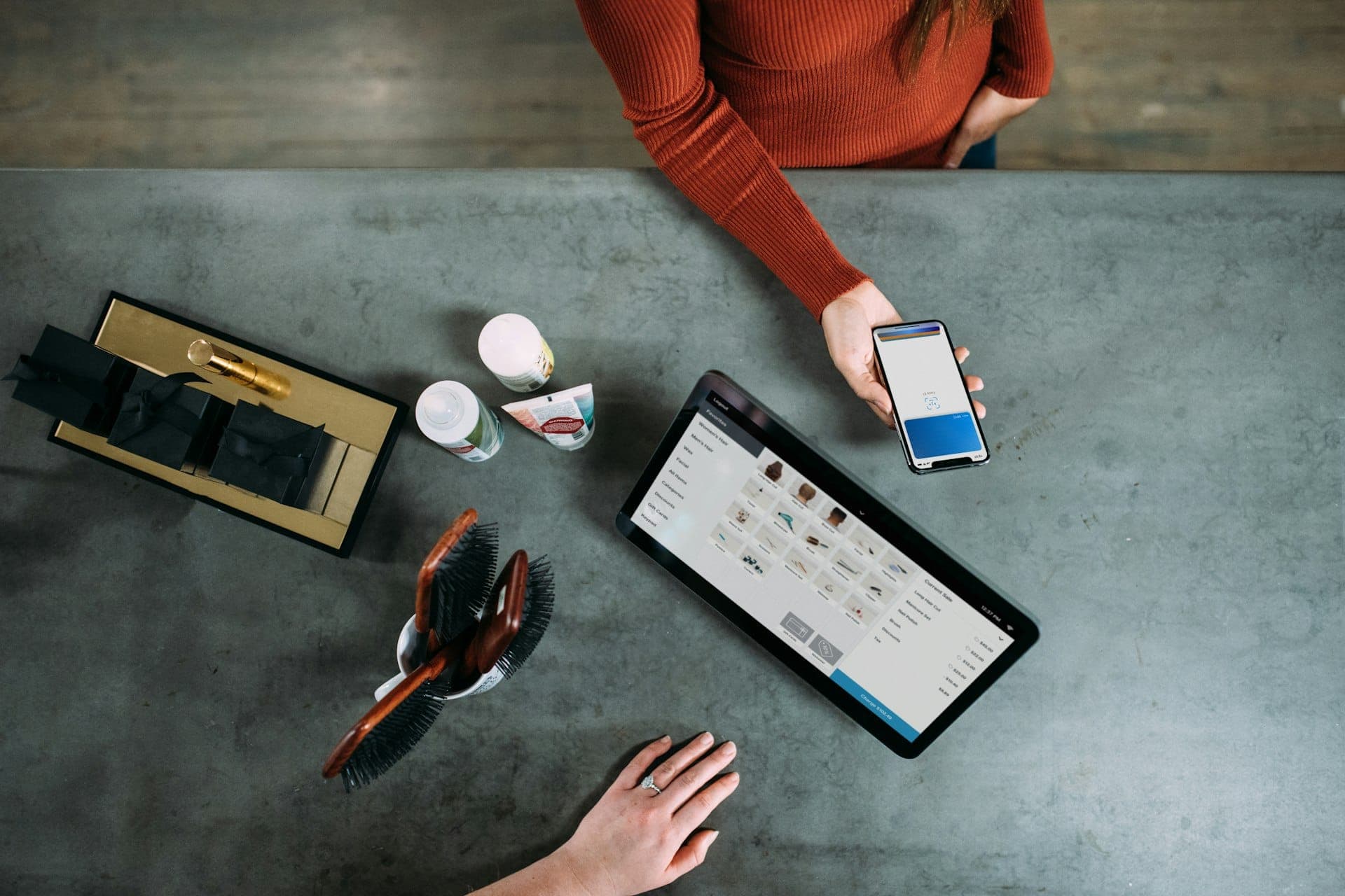 Customer paying with a smartphone at a shop counter next to a tablet point of sale