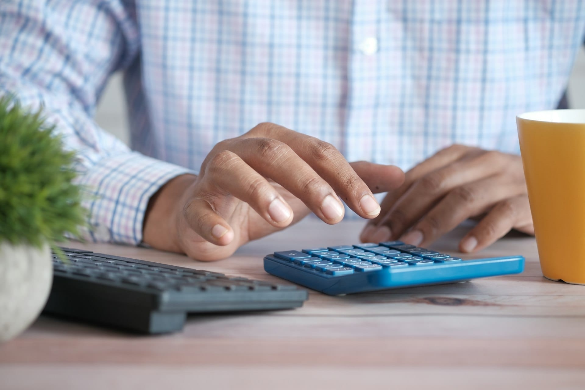 Hands using a calculator and a keyboard on an office desk